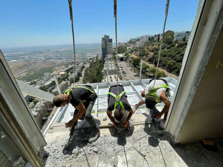 צוות עובדים מתקן מרפסת בבניין מגורים בעבודה בגובה (סנפלינג)